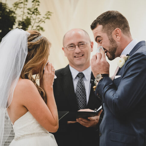 A bride and groom wipe their noses with tissue during their wedding ceremony the Wyche Pavilion in Greenville, SC.