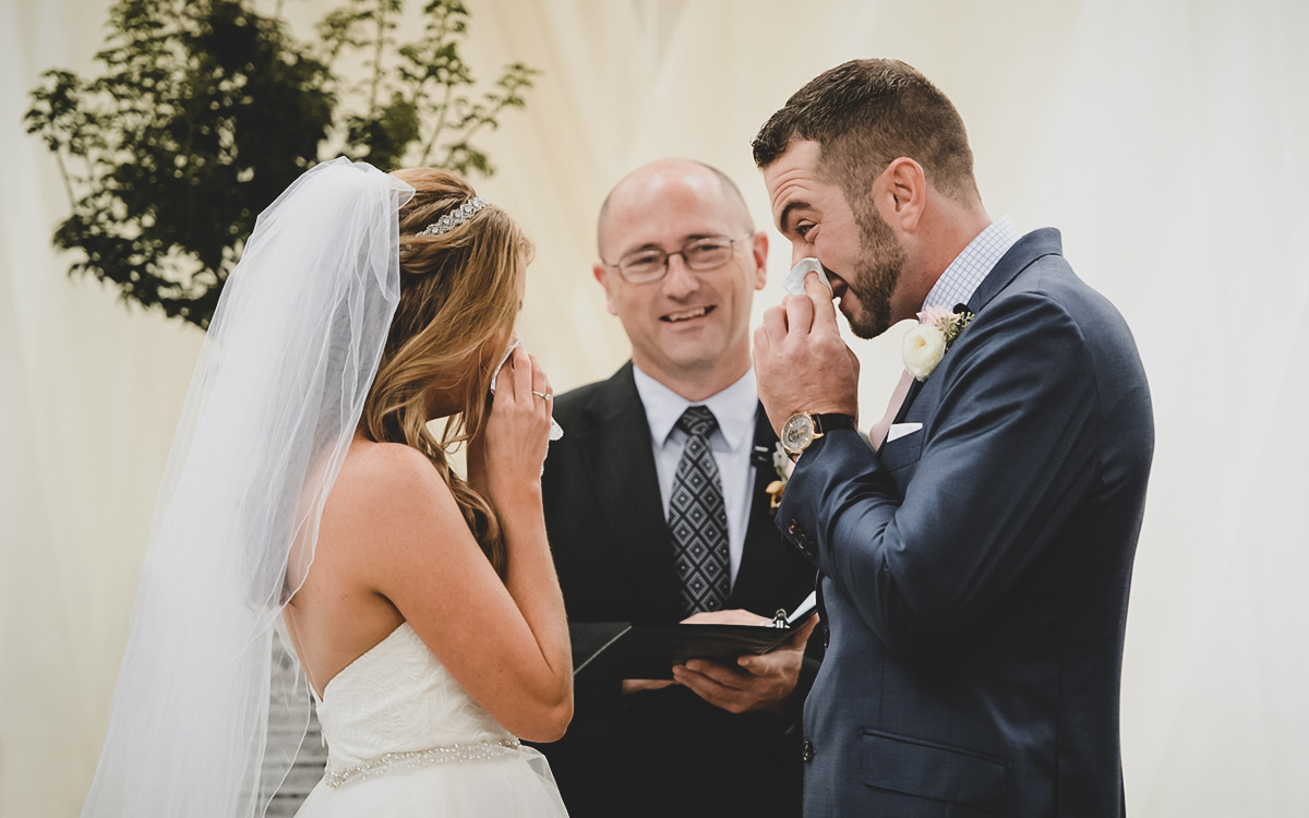 A bride and groom wipe their noses with tissue during their wedding ceremony the Wyche Pavilion in Greenville, SC.