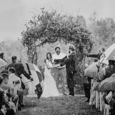 Rain begins to pour during an outdoor wedding ceremony.