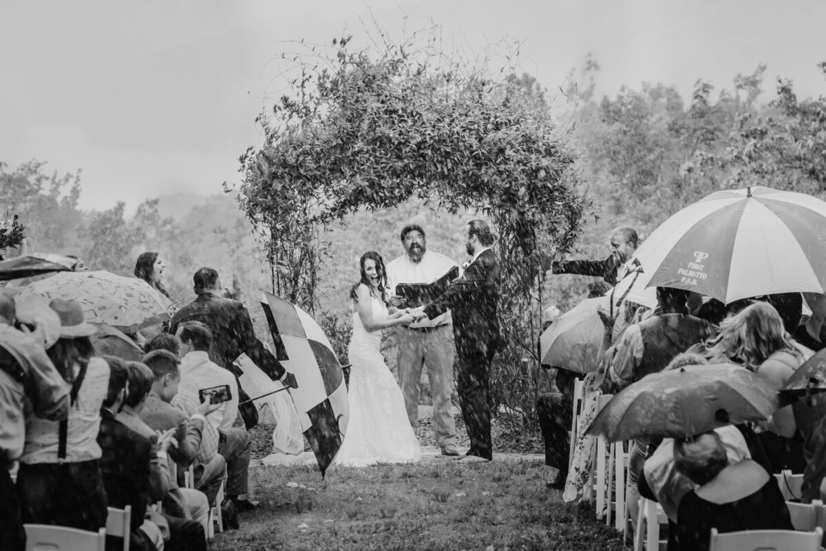 Rain begins to pour during an outdoor wedding ceremony.