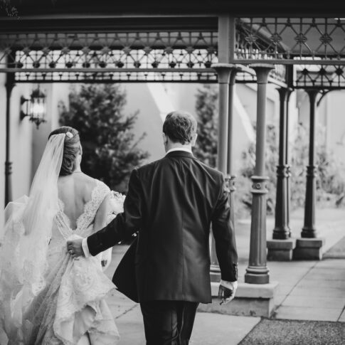 A bride and groom walking to their awaiting chauffeur and Rolls-Royce.