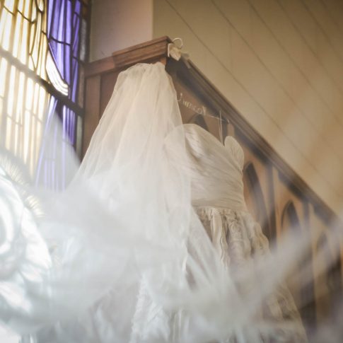 A wedding dress hangs in preparation for the big day on the edge of the wooden detail of the sanctuary of Bethel United Methodist Church in Spartanburg, SC.