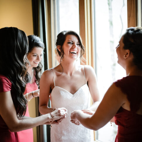 The bride grasps the hands of her bridesmaids in laughter moments before the commencement of the ceremony.