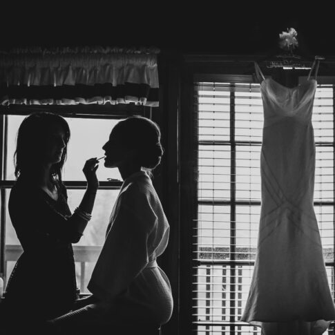 The silhouette of the bride getting ready is perfectly captured as her dress hangs from the window beside her.