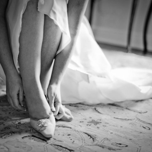 A bride slips on her shoe as she gets ready for her upcoming wedding.