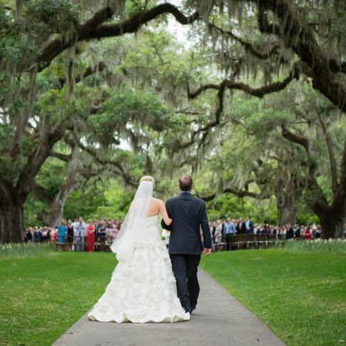 A bride, being escorted on the arm of her father, approaches the altar during a ceremony at Brookgreen Gardens.