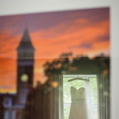 Reflecting in a framed photo of Tillman Hall at Clemson University, the brides alma mater, her wedding dress hangs softly on the window frame.