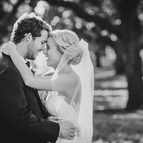 A black and white photograph of newlyweds embracing and laughing.