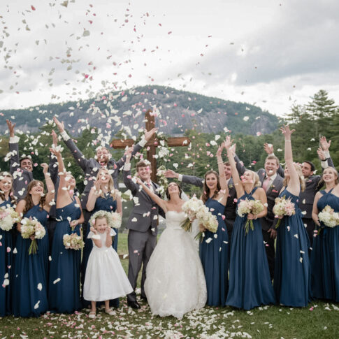 A wedding party throws rose petals in the air in celebration of the newlyweds at High Hampton Inn.