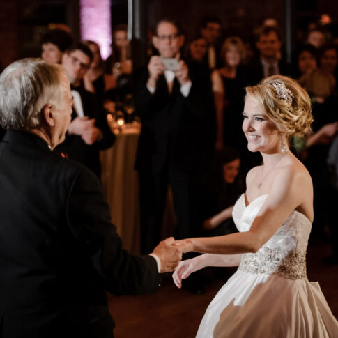 The bride happily smiles at her father mid-twirl during their father-daughter dance.