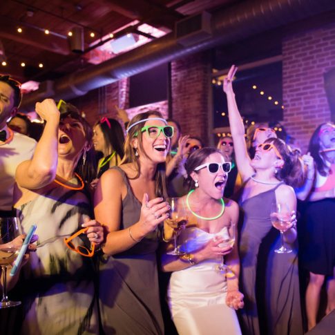 The bride, accompanied by her bridesmaids and guests, dance excitedly to the music of the live band during a wedding reception at the Wyche Pavilion in Greenville, SC.