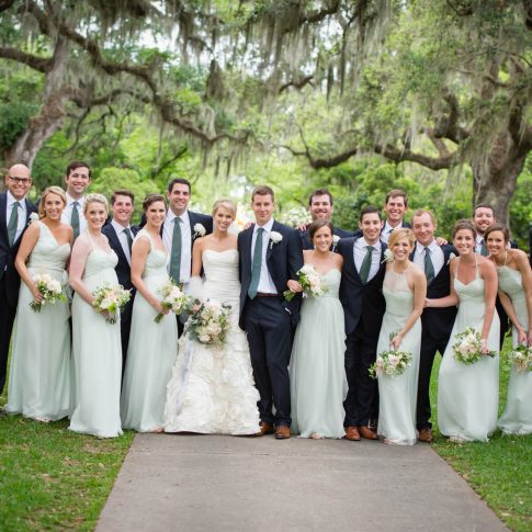The entire wedding party pauses and smiles in front of the huge live oak trees of Brookgreen Gardens.