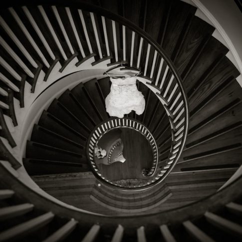 A lace wedding gown hangs in the circular staircase at Lowndes Grove Plantation.