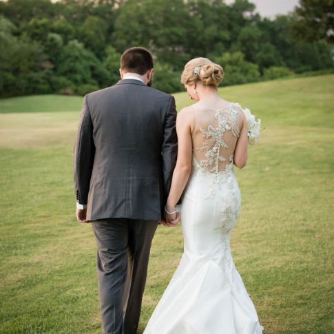 A bride and groom walk hand-in-hand over the golf course at the Madren Center in Clemson, SC.