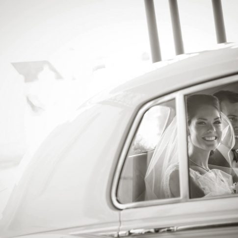 The bride smiles into the camera as the newlyweds prepare to depart for their honeymoon.