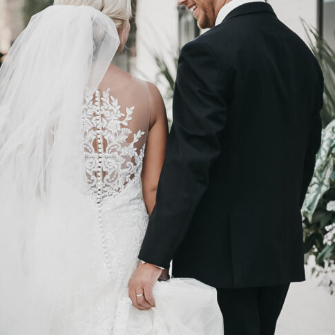 A groom carries his brides train as they walk the streets of downtown Charleston, SC.