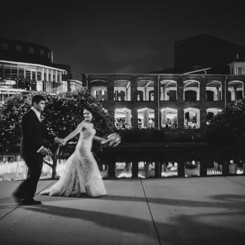 Newlyweds walk hand-in-hand along the sidewalk outside of the Wyche Pavilion as they prepare to join their reception.