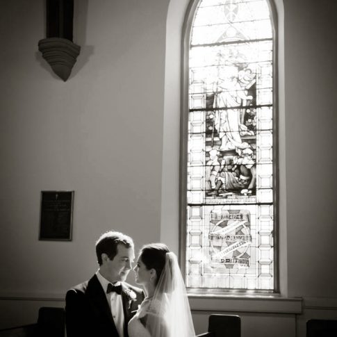 The bride and groom stand in between pews in the St. Johns Episcopal Church where they will be married.