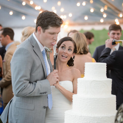 During the cake cutting during the reception, a bride excitedly watches her new husband sample the delicious cake.