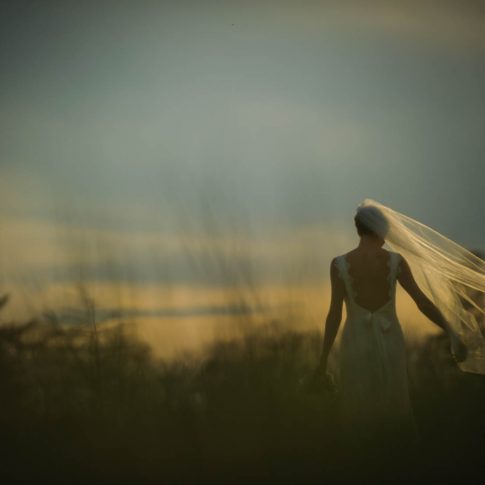 A brides veil blows in the wind as she looks off into the stormy horizon during a bridal portrait session.