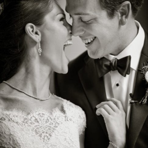 A happy couple looks lovingly towards each other and shares a laugh on their wedding day.