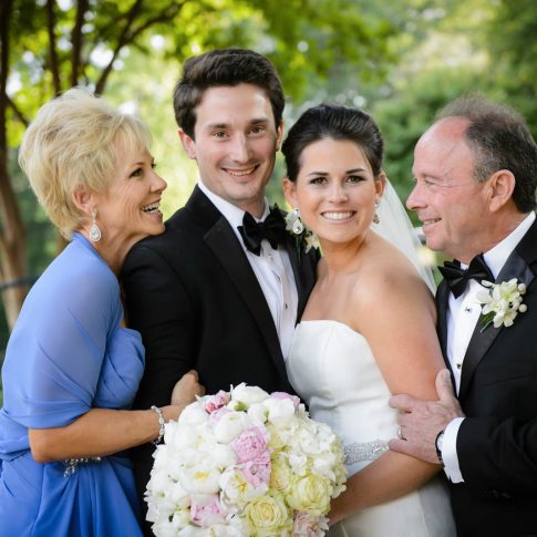 Parents of the bride and groom lovingly embrace the young couple in a moment of excitement and support for the couple.