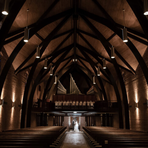 A wide angle photograph of Westminster Presbyterian Church in Greenville, with a bride and groom hugging at the far end of the isle.