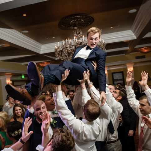 Guests at the reception taking place at the Orangeburg country club lift the groom in excitement and celebration.