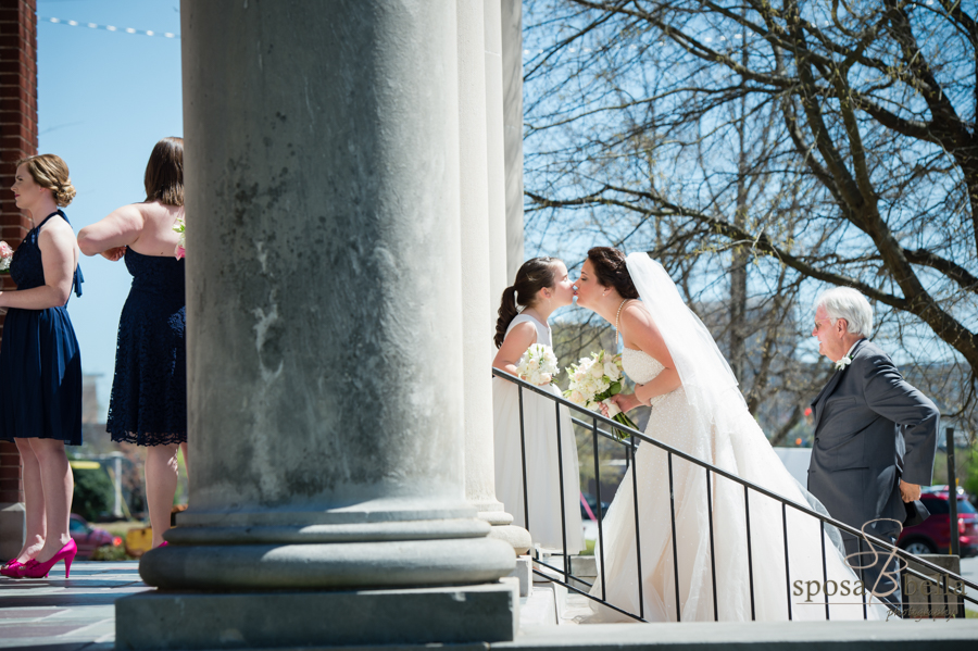 A kiss for good luck from a flower girl to the bride as they prepare to enter the wedding ceremony.