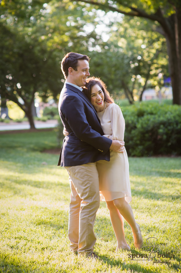 Engaged couple happily embraces underneath the warm sunshine. 