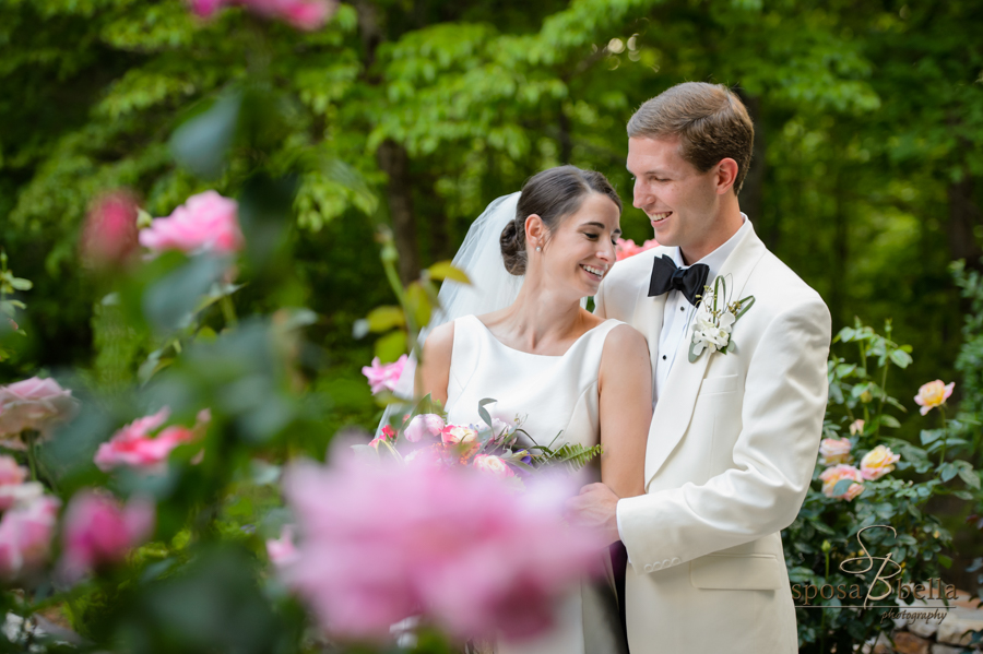 The bride and groom snuggle among roses in the garden shortly after the ceremony. 