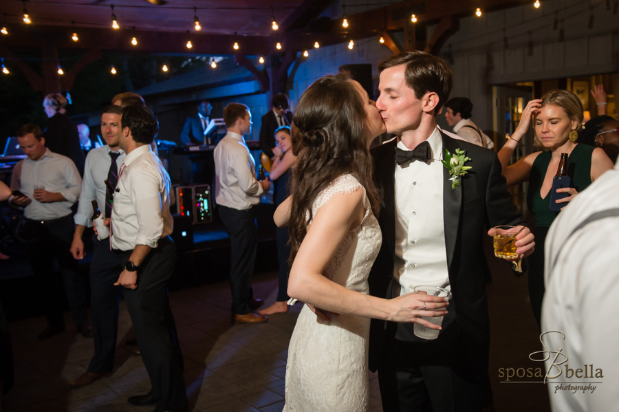 Bride and groom kiss while dancing at their reception. 