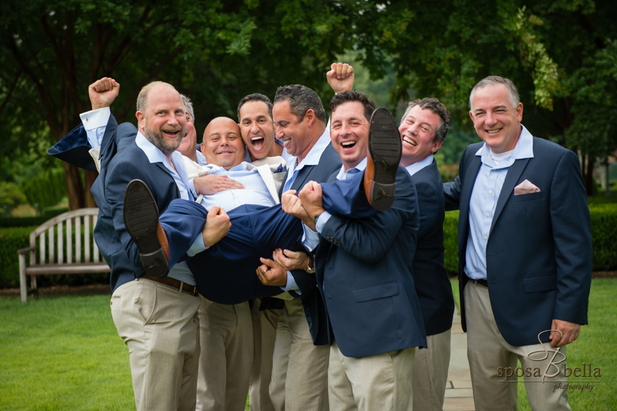 The groomsmen jokingly lift up the groom during their group photo. 