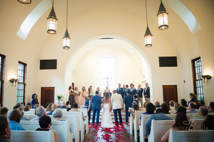 The bride, groom, and their families all stand at the front of the chapel. 