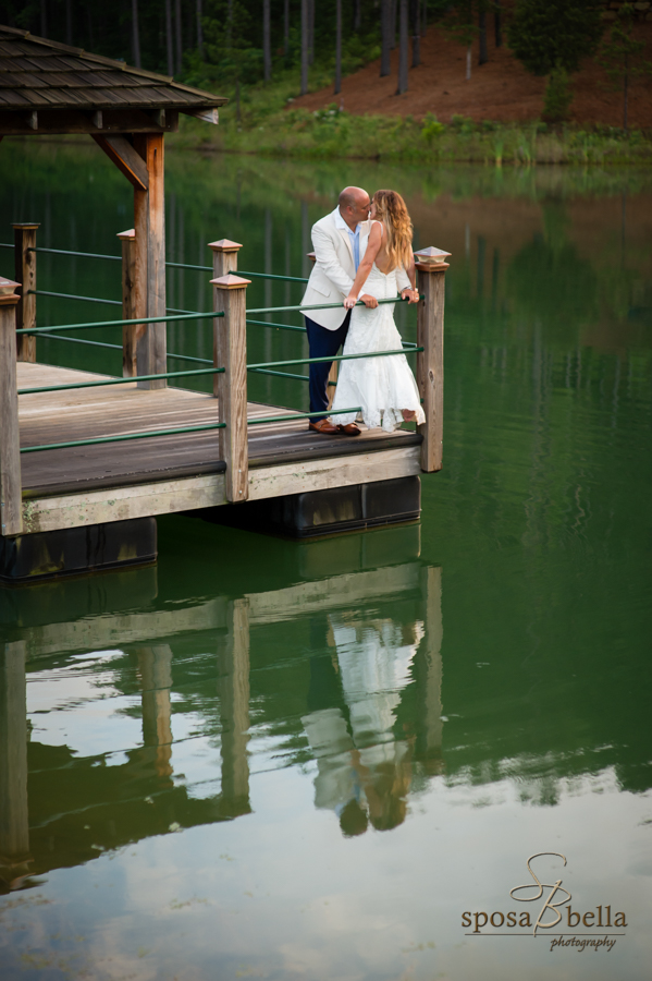 The bride and groom kiss on the dock overlooking part of Lake Keowee. 
