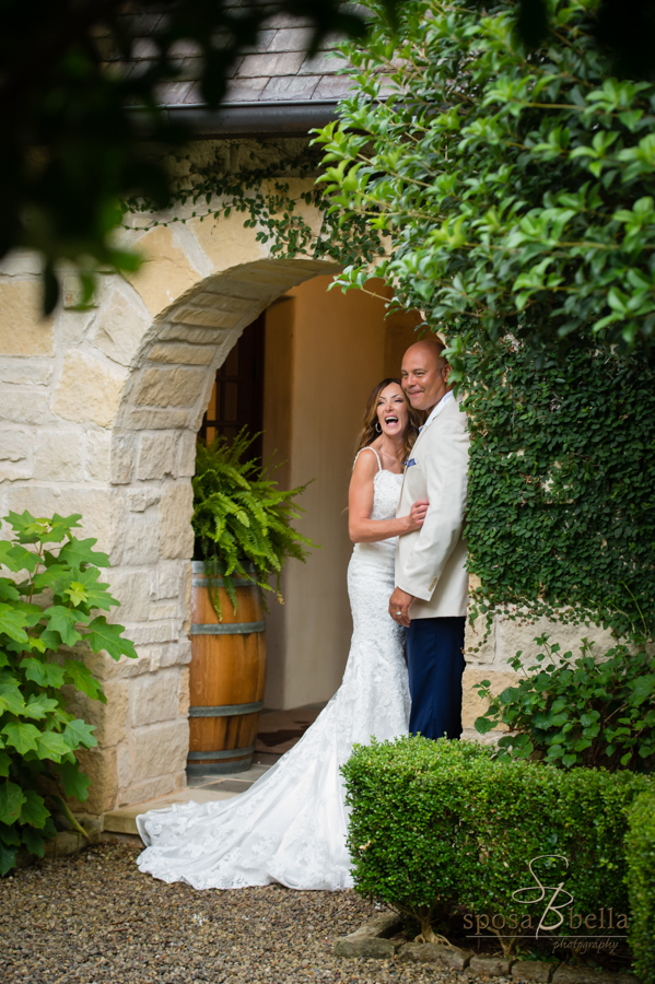 The bride laughs while hugging her groom underneath the archway outside of the chapel at the Reserve at Keowee.