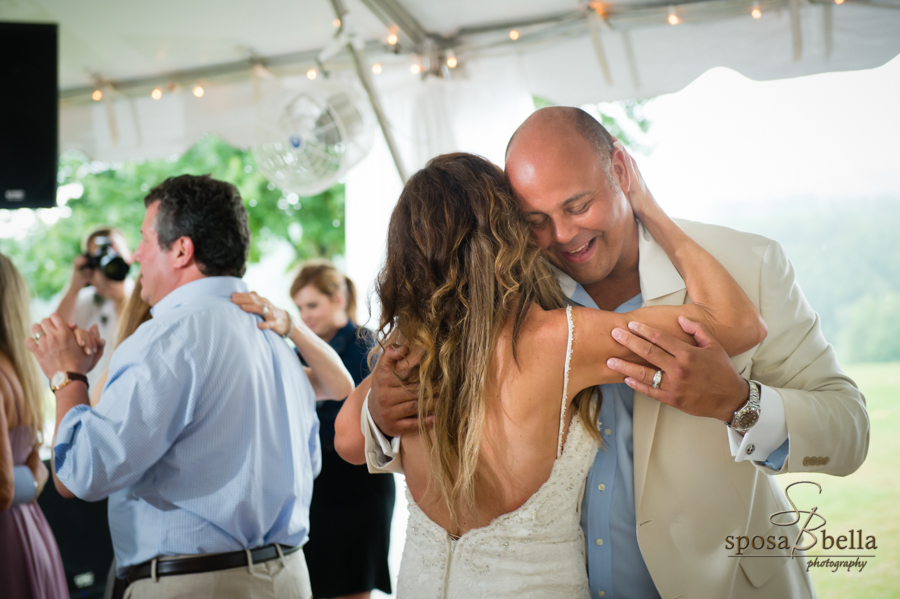 The groom smiles and hugs his wife during their first dance. 