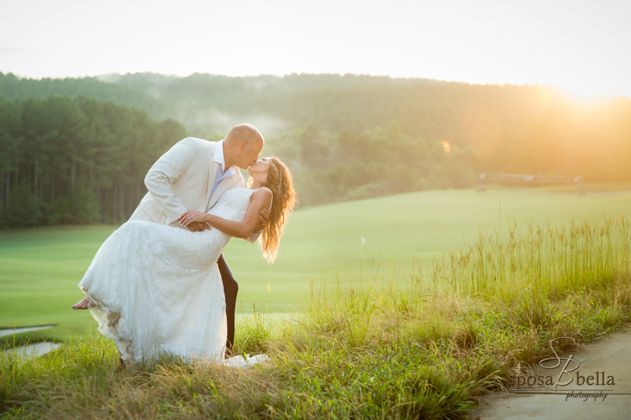 The groom kisses his wife as the sunset shines in the distance. 