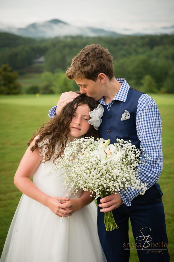 The brides son kisses his sister and holds her flowers after the ceremony. 