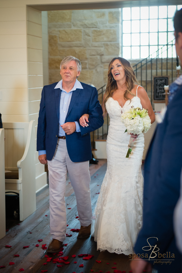 The bride laughs as she is escorted down the aisle. 