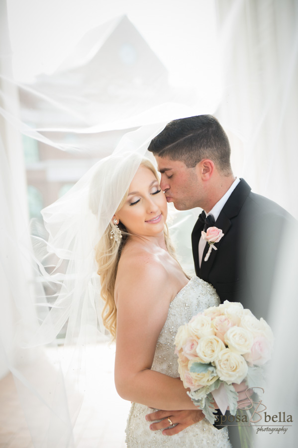 Groom leaning in for a quick peck on the Bride's cheek underneath the Bride's veil.