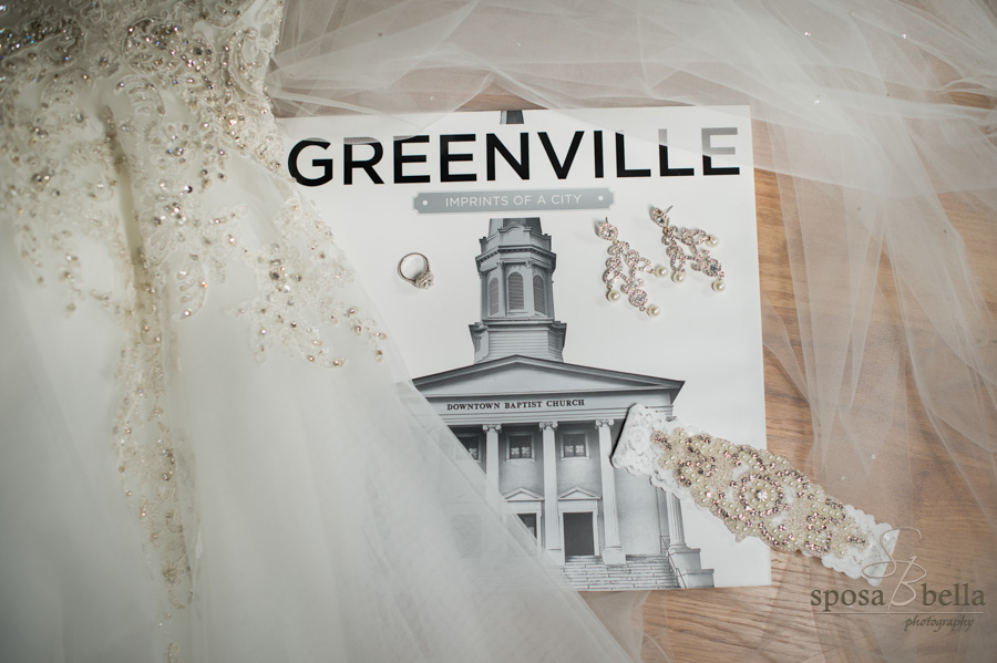 City of Greenville coffee table book with a bride's dress, garter, engagement ring, and earrings laying on it.