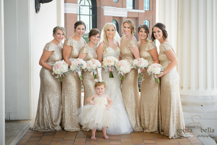 Bride, bridesmaids, and flower girl pose for a photo on the church entrance.