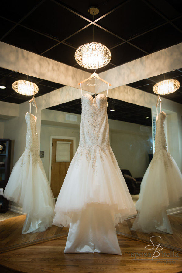 Wedding dress hangs in bride's getting ready room.