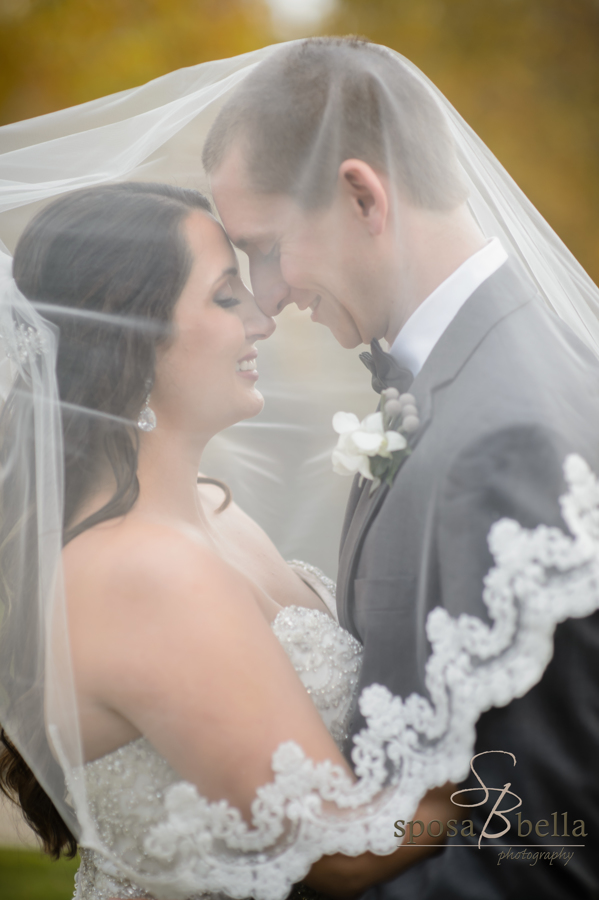 The couple tenderly embraces under the bride's veil.