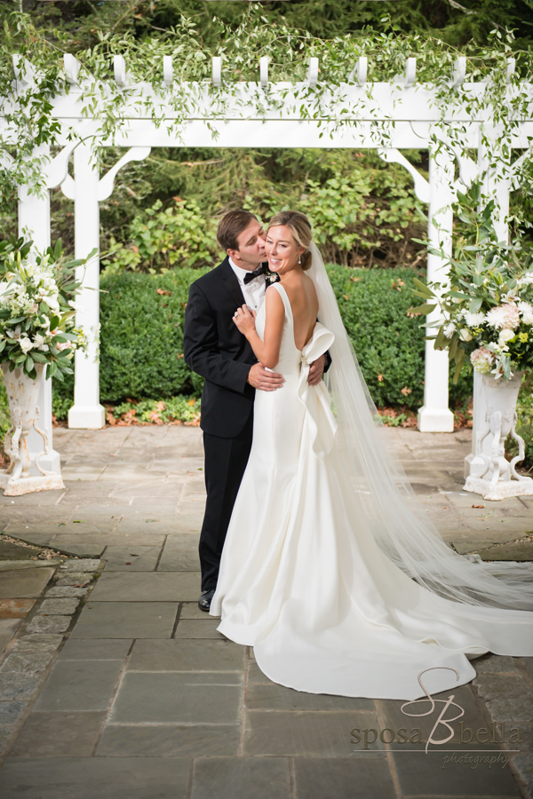 A blissful Charlie kisses Leland cheek under an ivy-covered trellis.