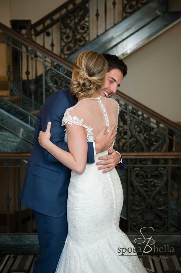 Groom hugs his bride with big smile on his face.