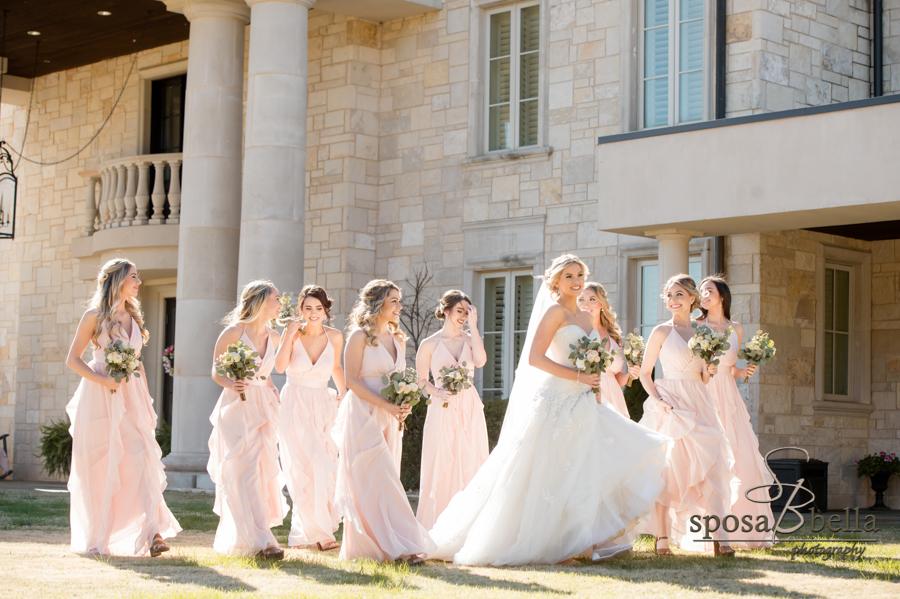 Bride walks through grass surrounded by bridal party.